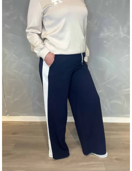 Navy blå jogging bukser med hvide sidestriber fra TIPPY, vist på model med hvid sweatshirt vist fra siden