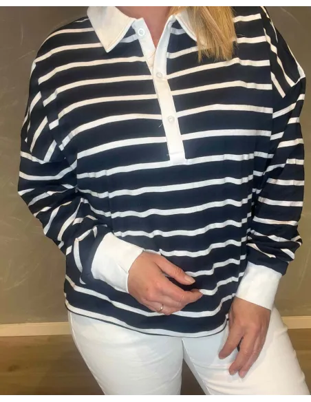Nærbillede af den stribede kvalitet og den hvide knaplukning på polo blusen