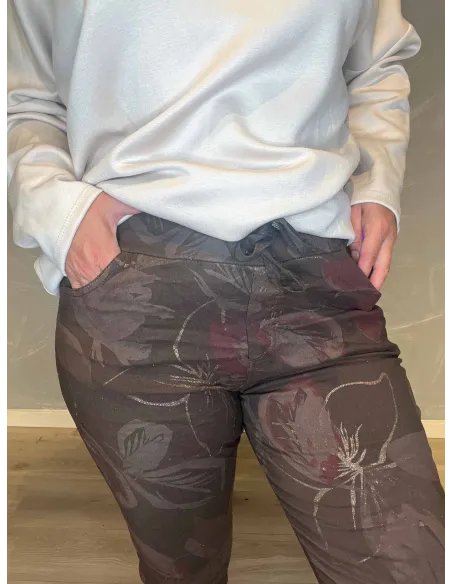 Nærbillede af blomsterprint og guld detaljer på brun strækbukser til kvinder - TIPPY"