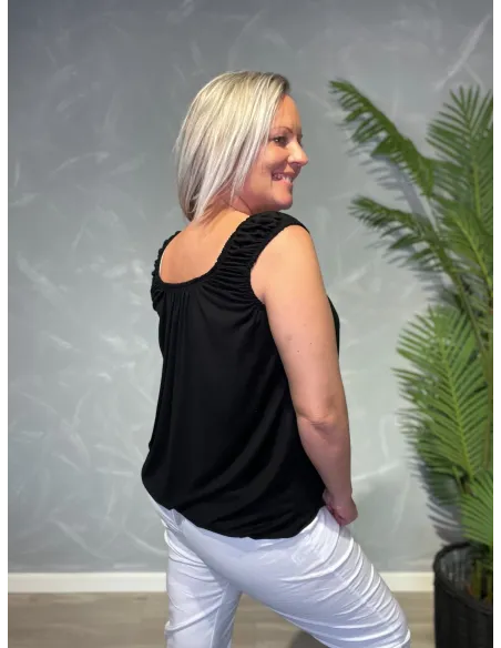 Komplet outfit visning med sort top og hvide bukser, set bagfra