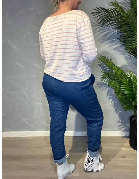 Jeans-farvede bukser med stræk fra TIPPY, vist på model med stribet top og sølvbælte, vist bagfra